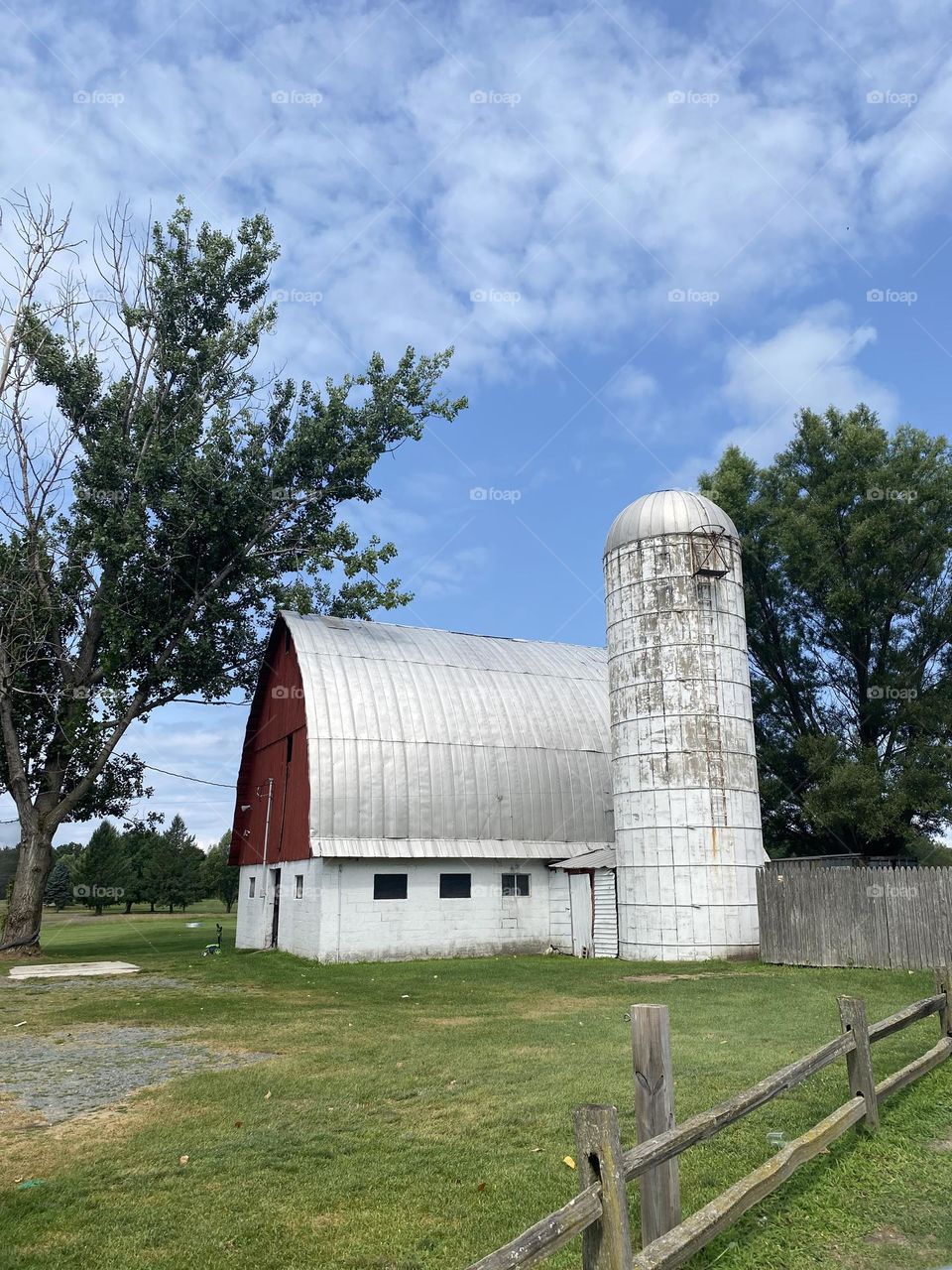 A barn with a silo in a charming rural daytime scene. 