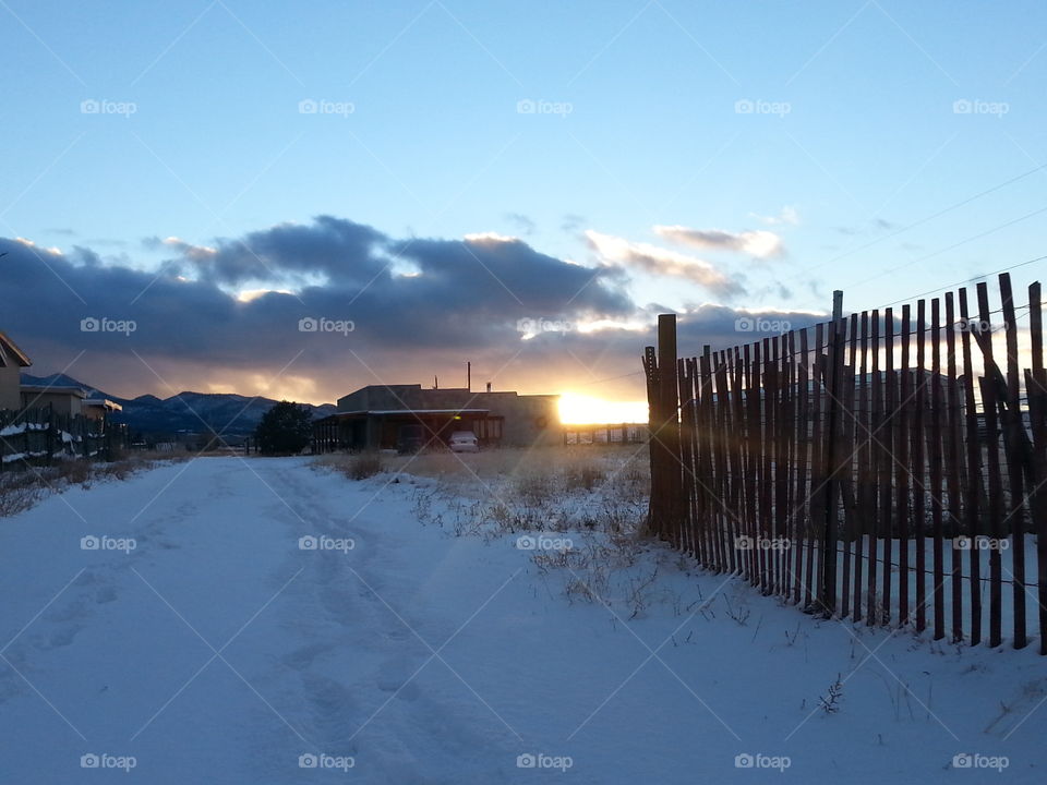 sunset on farm field snowy road