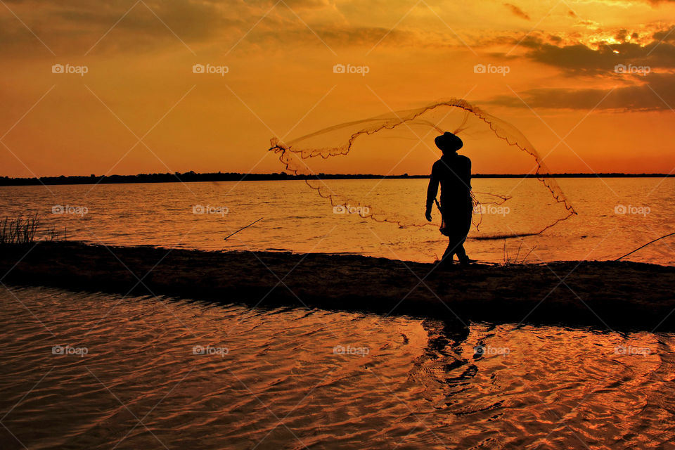Fisherman throw the nets under sunset, Banjarbaru, South Kalimantan, Indonesia.