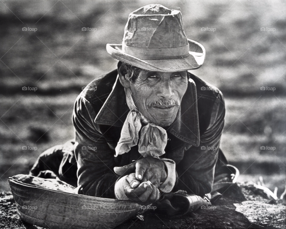 a mexican farm worker rests on the ground in a citrus orchard. migrant farm worker. southwest usa by arizphotog
