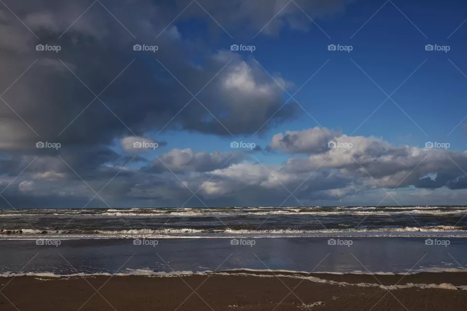 Beautiful sky with big clouds, beach, waves in the sea