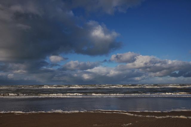 Beautiful sky with big clouds, beach, waves in the sea