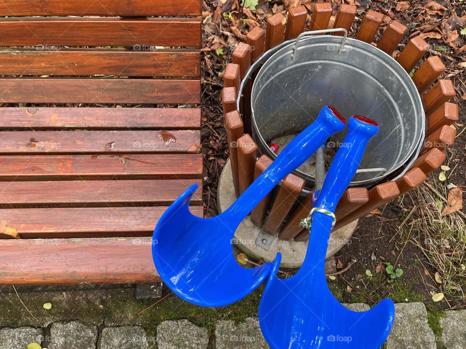 Close-up of two blue crutches standing next to a brown wooden bench in a trash can