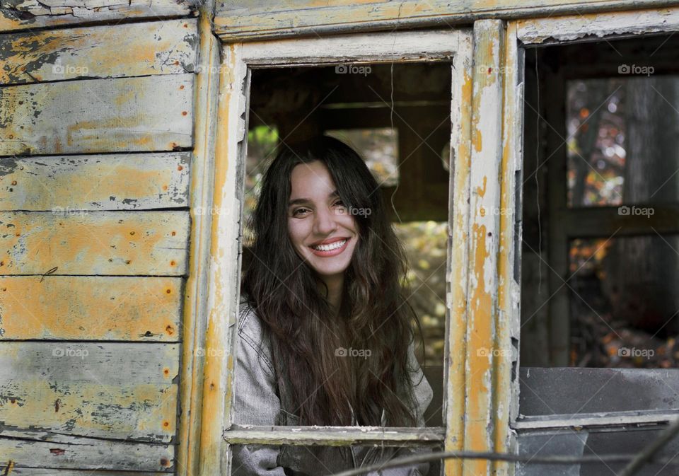 Smiling beautiful woman on the window of abandoned house