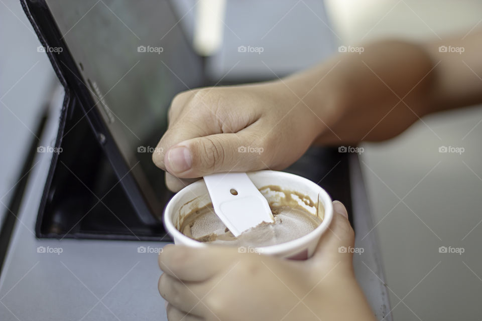 Hand boy holding the spoon Ice cream scoop in a cup.