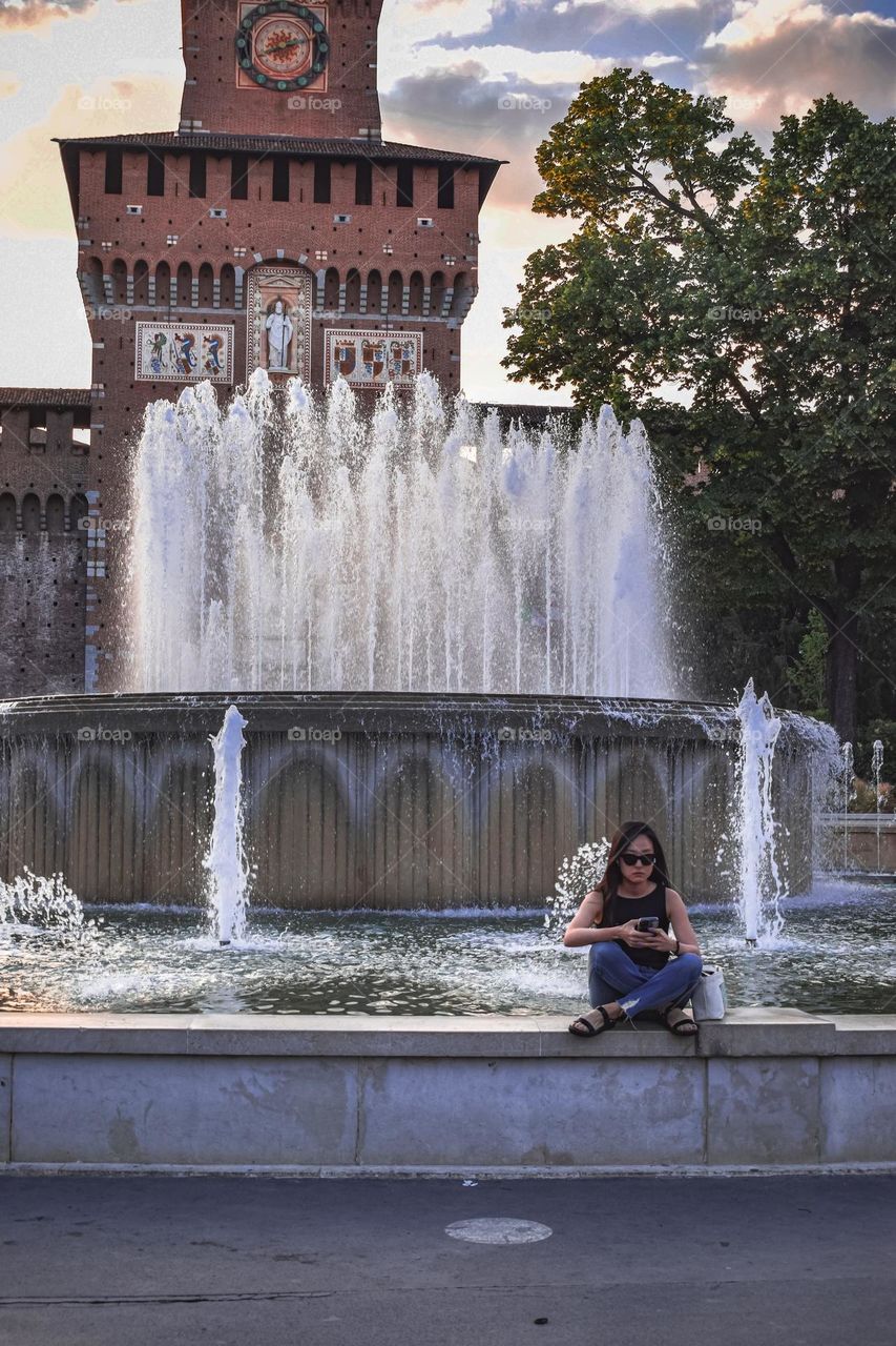 A woman sitting by a fountain