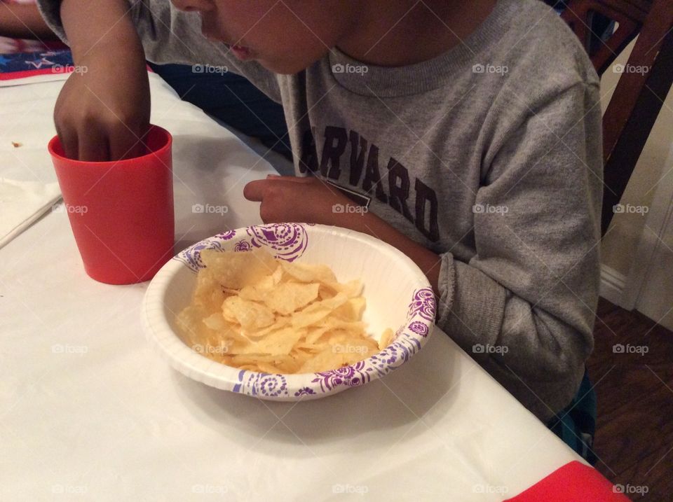 Child dipping potato chips in drink. Child dipping potato chips in drink