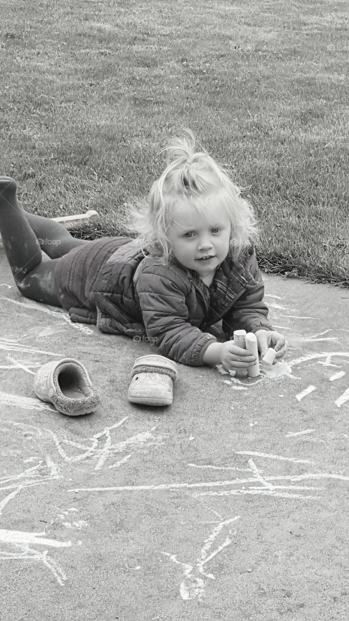 Little girl drawing with chalk on road