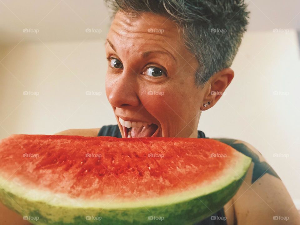 Woman eating a large piece of Watermelon, delicious summertime treats, woman with mouth wide open 