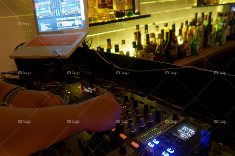 DJ mixing music at a bar club using a console and CD players. Dj mixing music using a laptop a usb and two professional cd players.