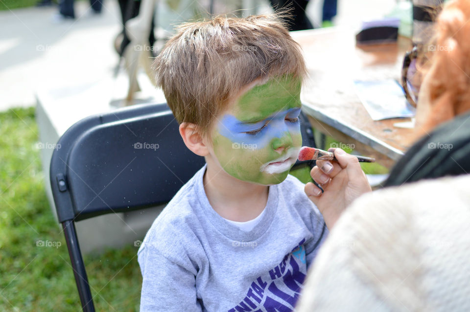 Young boy getting his face painted for Halloween