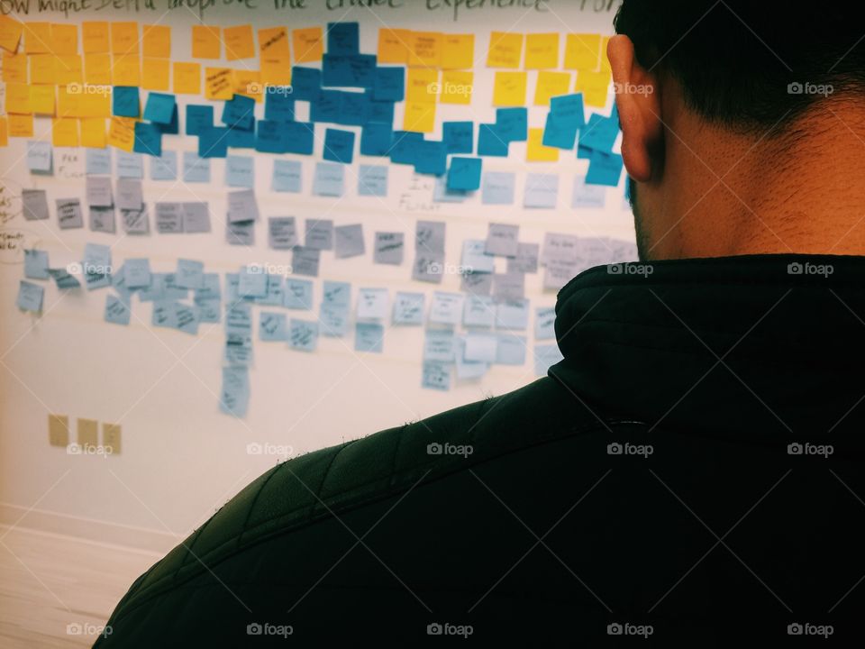 Person looking at the sticky notes on the wall action items after a business meeting at office 