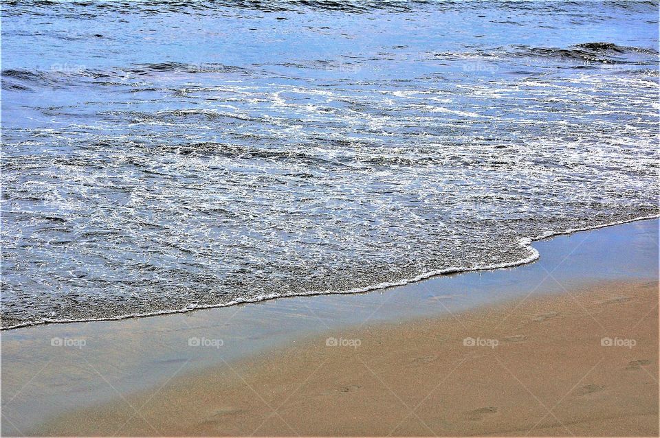 Beach Waves with Footprints in The Sand