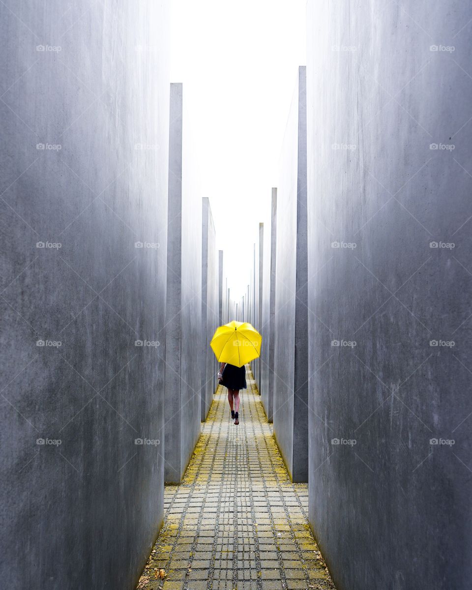 Rear view of woman with umbrella in corridor