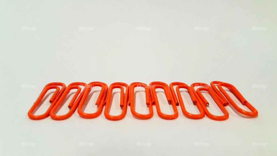 Orange paper clip in a row