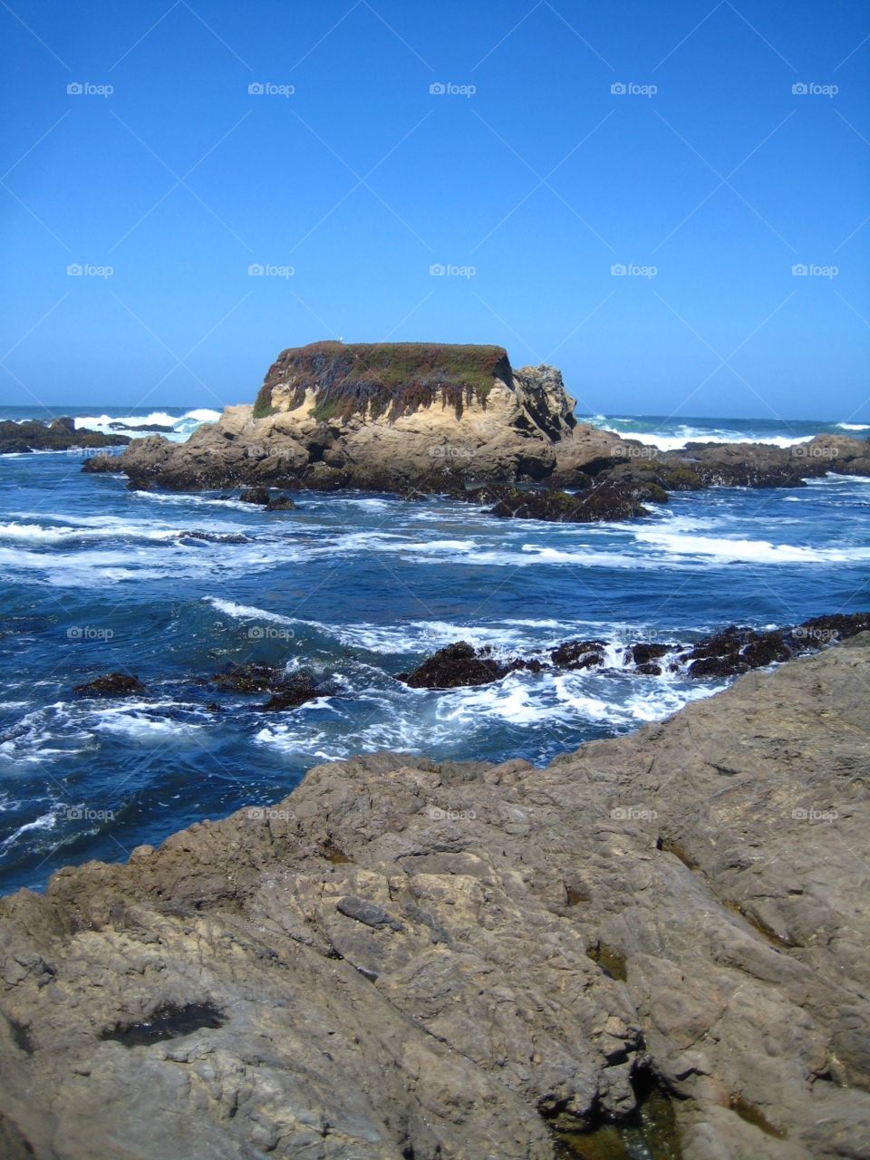 Rocky island. Blue foaming sea and rocky coastline