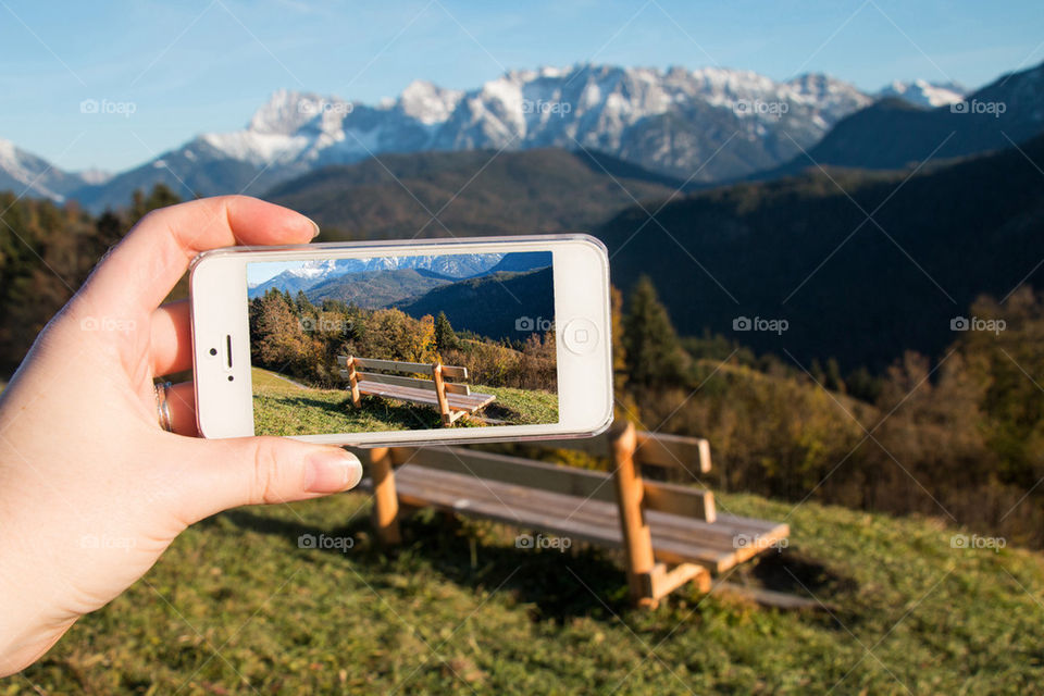 Person hand photographing empty bench