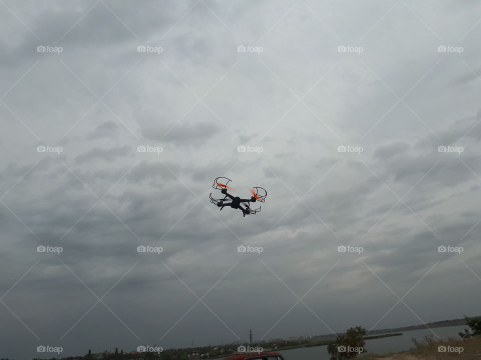 The drone flying in the grey sky