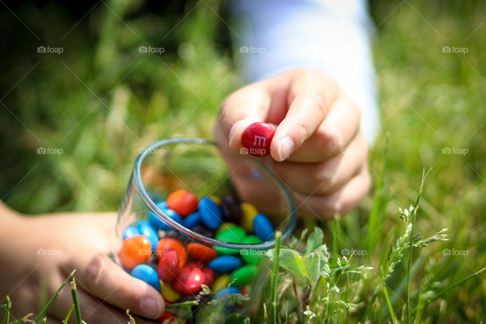 Child is holding glass with M&Ms chocolates