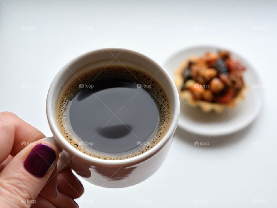 cup of coffee in the female hand with sweets on a white table background eating at home