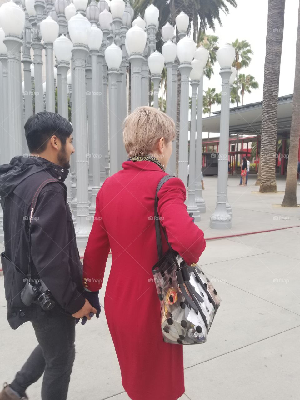 couple walking outside urban landmark of streetlights in city with red coat