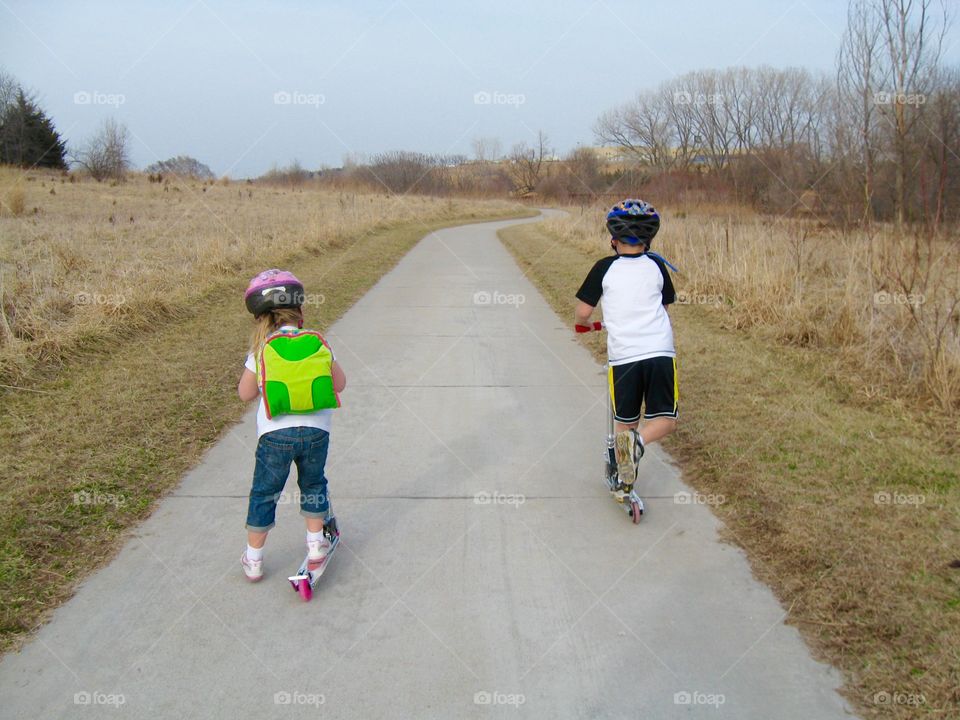 Scooter riding. Siblings enjoying a warm fall day riding scooters