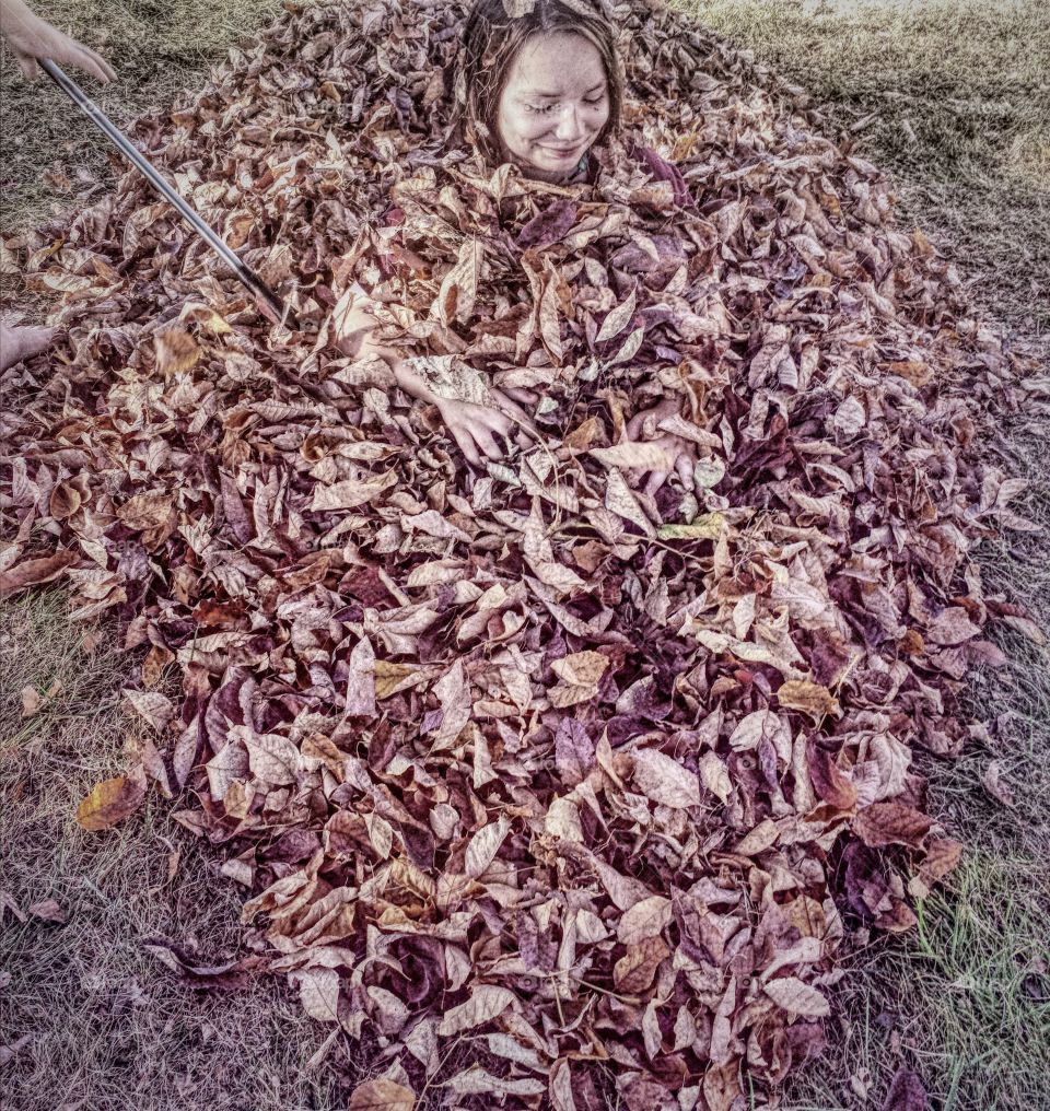 Girl inside dry autumn leaves