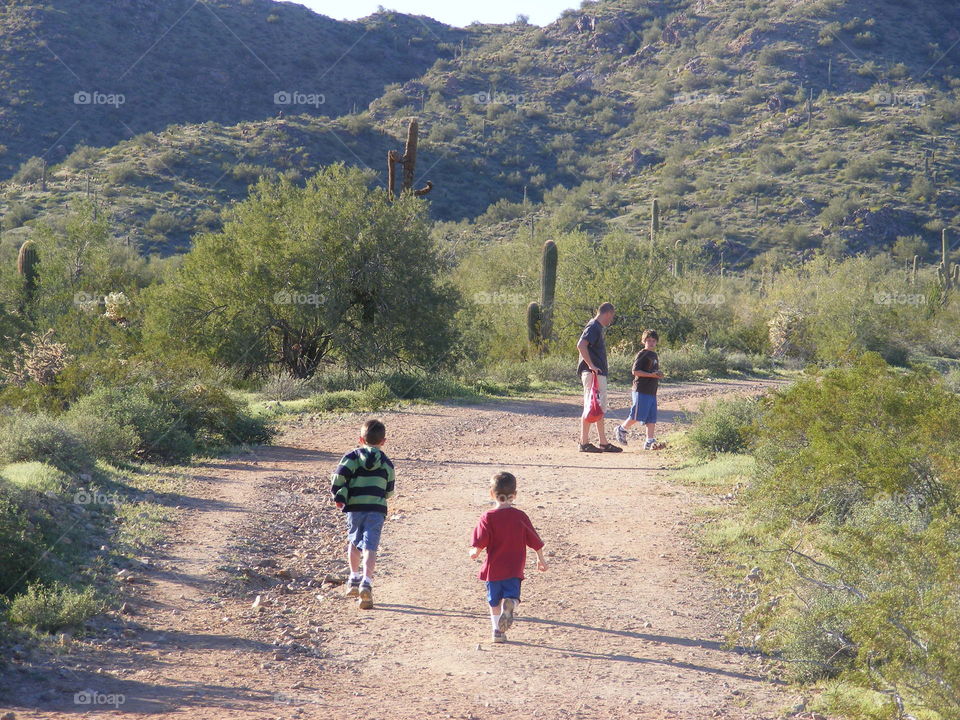 This man and three children are hiking a desert mountain trail in Arizona.