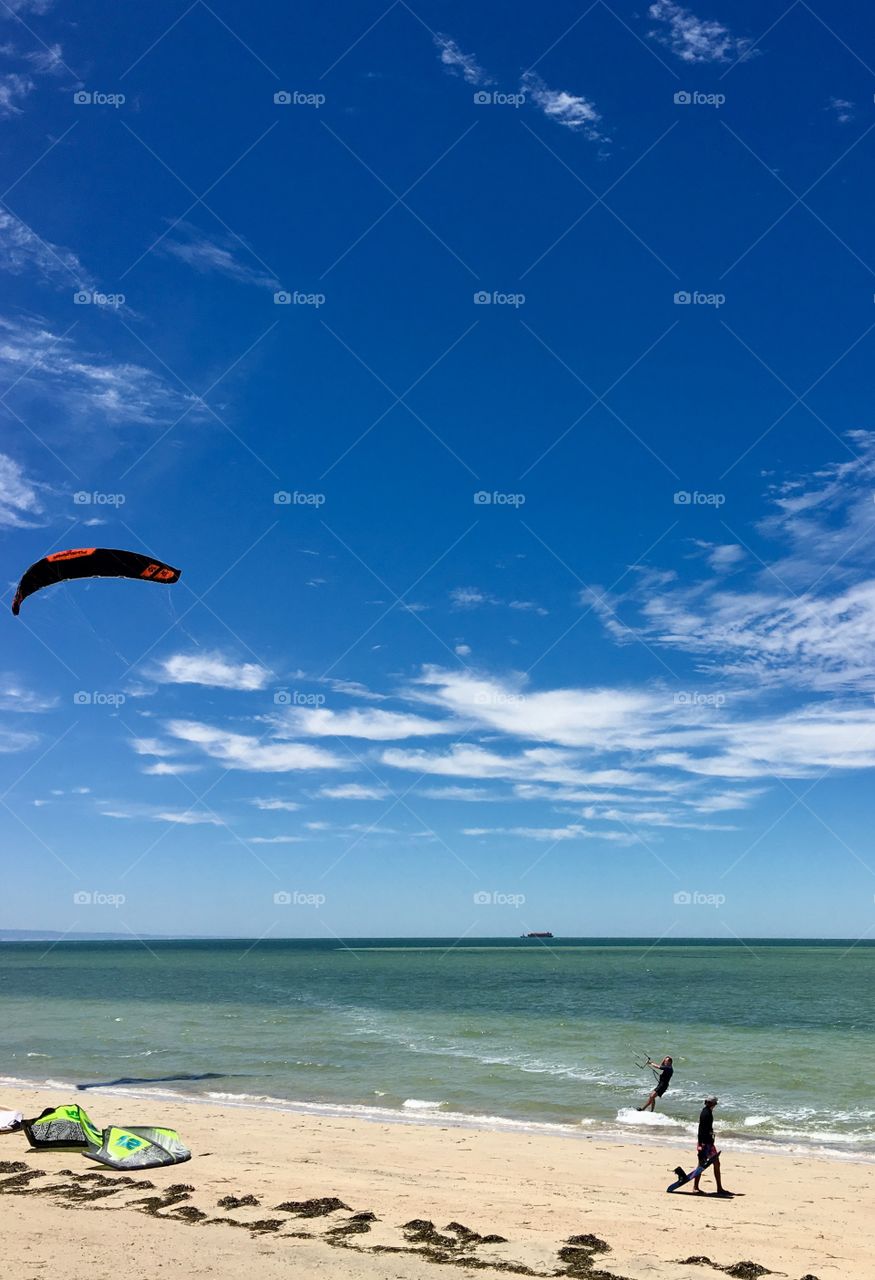 Kiteboarding, colourful kite, skimming along the seashore 