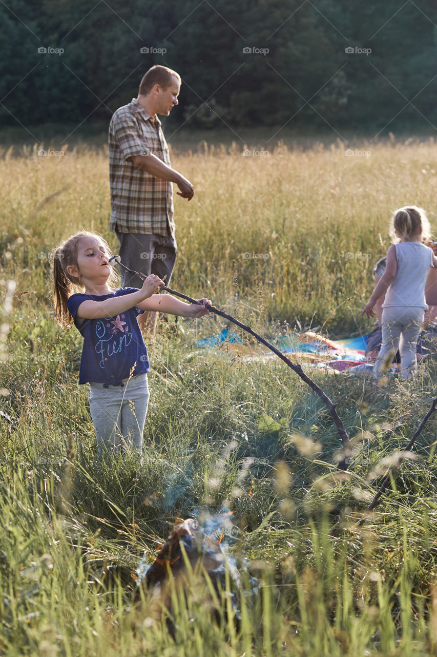 Little girl eating a marshmallow after roasting it over a campfire on a meadow. Candid people, real moments, authentic situations