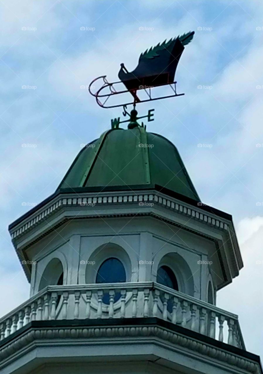 Weathervane with cupola atop large store.