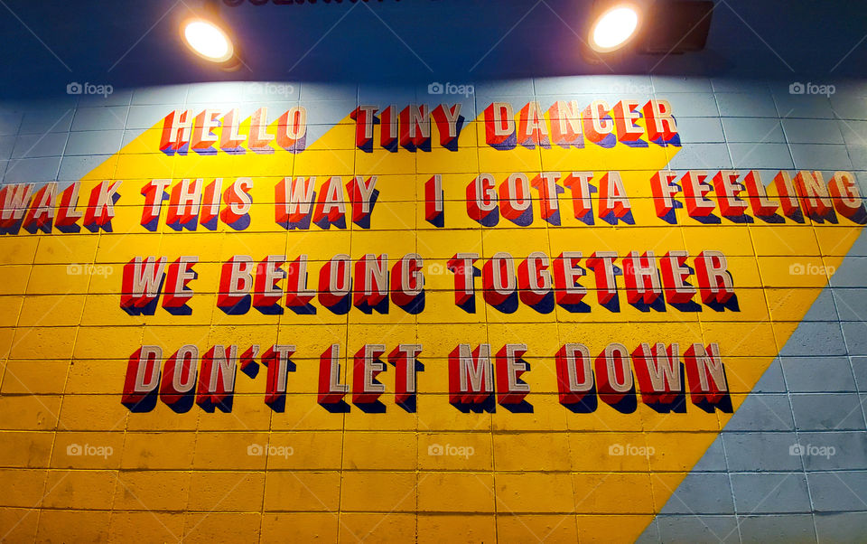 A wall is painted with the names of assorted song titles