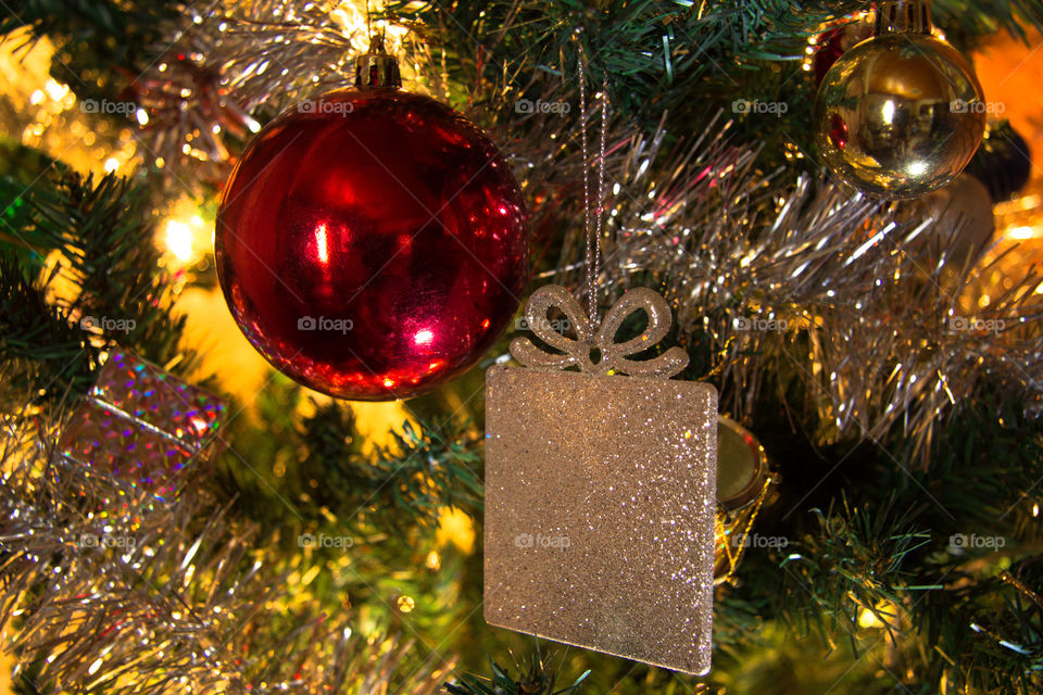 Christmas ornaments in a tree with some lights as backlight