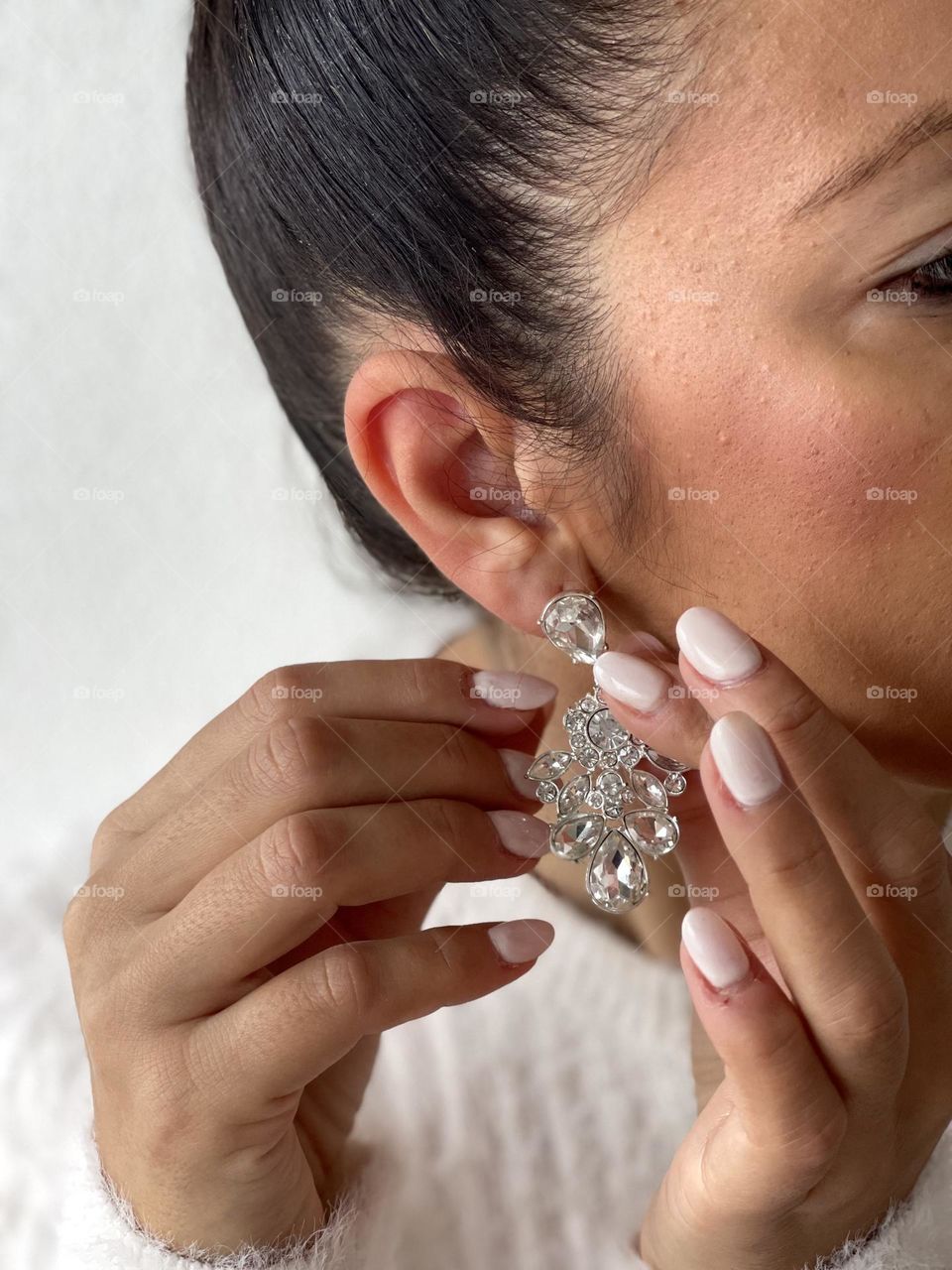 Woman in the act of wearing a crystal earring, girl wearing jewellery