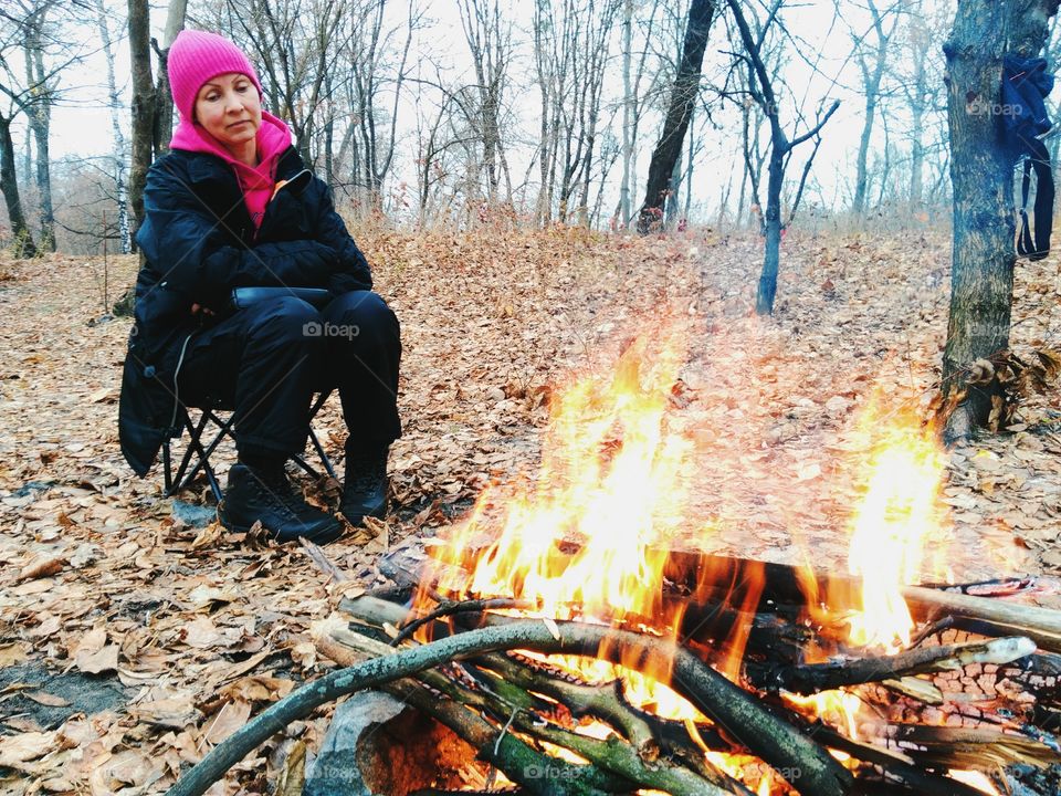 girl sitting by the fire on the nature, autumn 2016