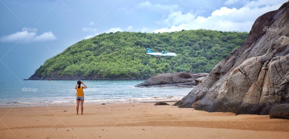 A traveller is taking picture of a landing airplane