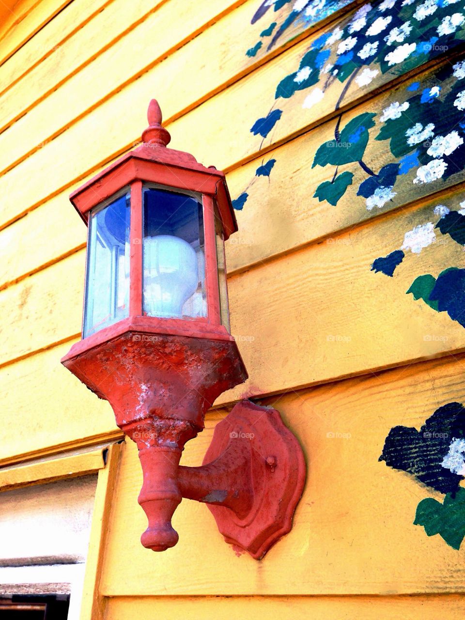 Old house and light fixture on bright yellow siding.