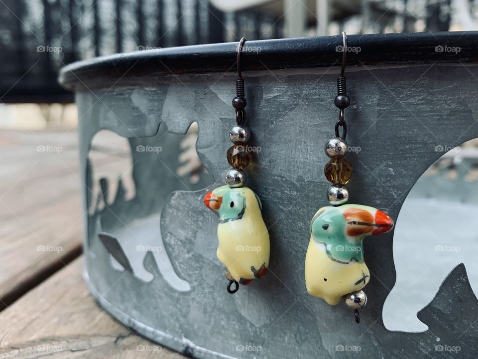 Yellow bird earrings, hanging from a tin pan. Handmade jewelry is the best. This was a gift from my child. 