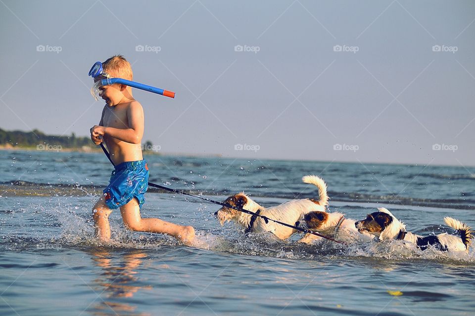 Running together. Boy at the beach with som fury friends