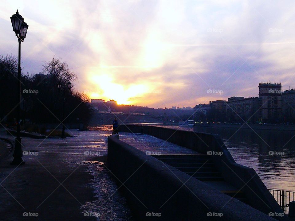 Sunset in winter, ice on asphalt, frozen river. December evening in a park, Moscow, Russia