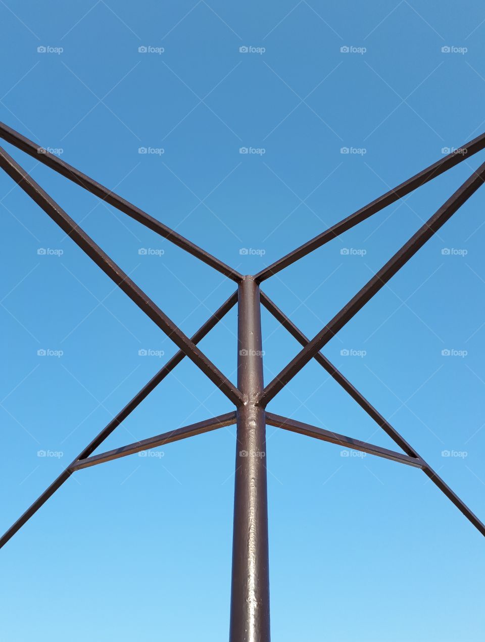 Black metal construction at blue sky background. Symmetry.