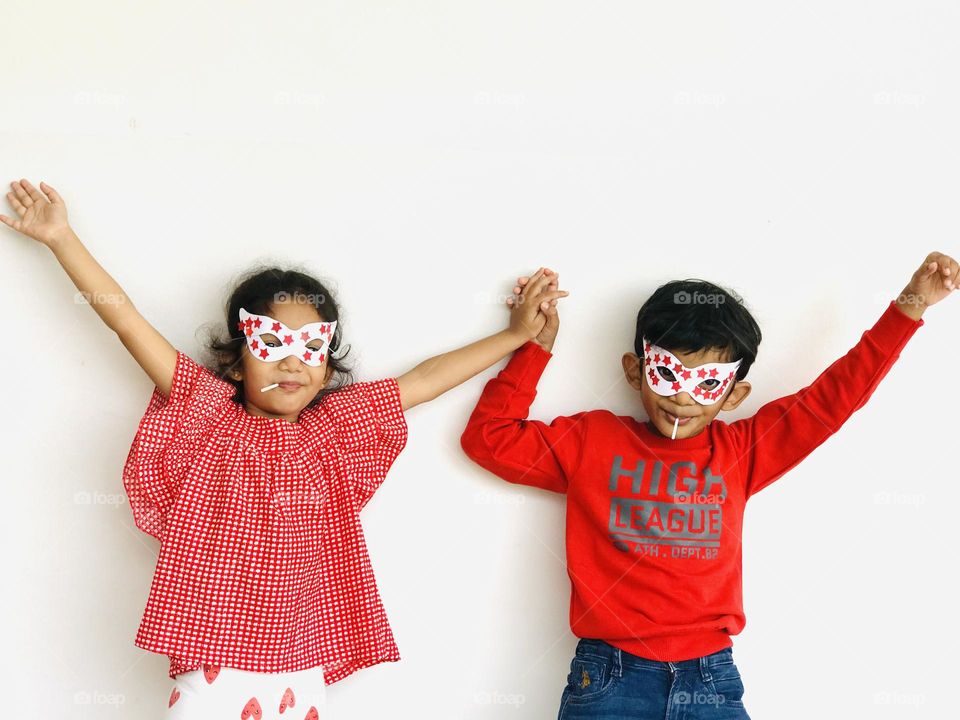 Brother and sister making fun by with lollipops in their mouth and smiling 