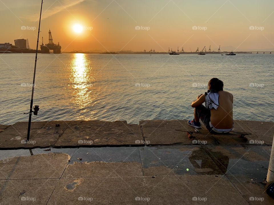 Boy on skateboard looking sunset 
