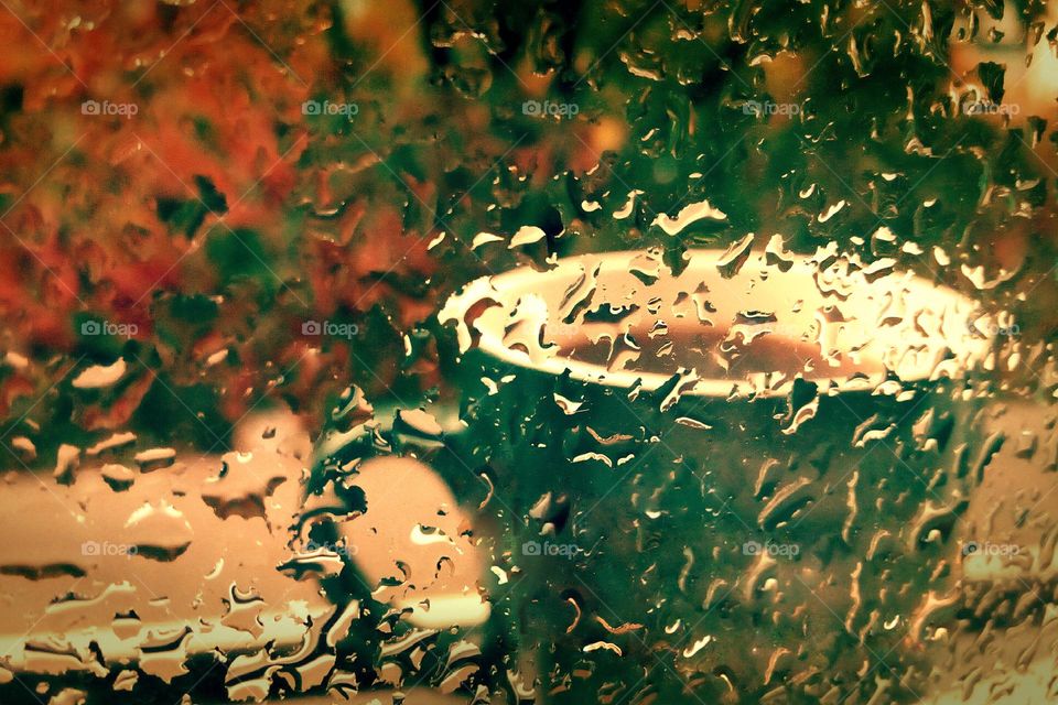 Rainy day, raindrops on the window and a coffee cup outside