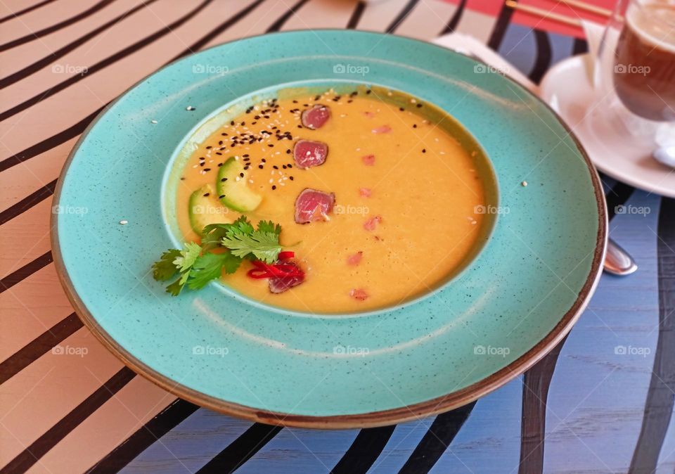 orange soup puree with tuna and salmon, very tasty, soup on the table, lunch,