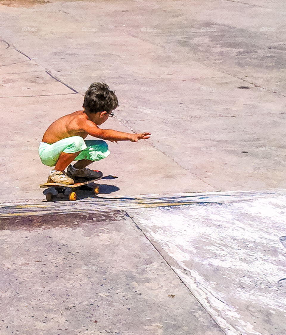 Shirtless boy sitting on skate