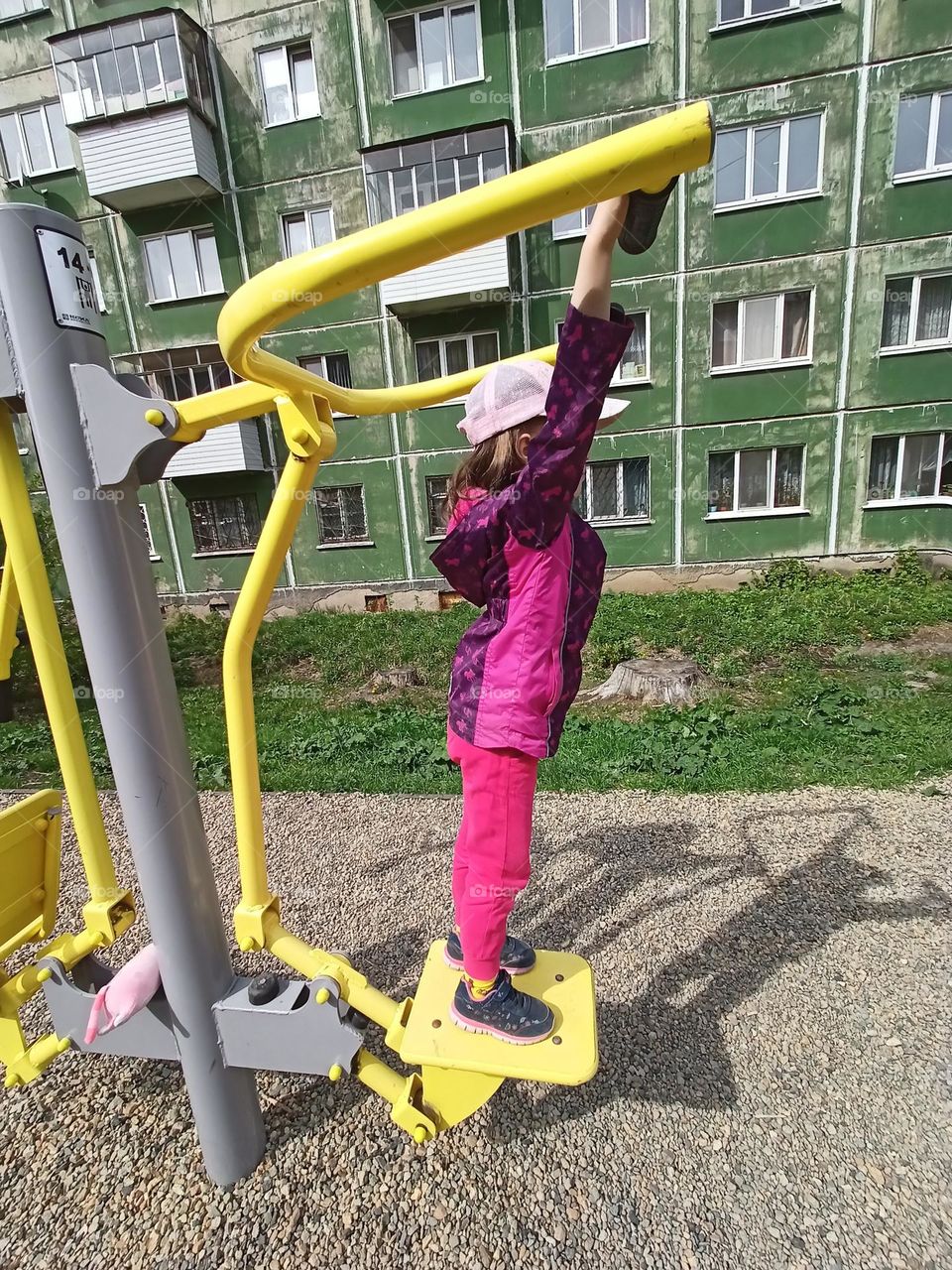 sports, fitness equipment, training on the street, a child and exercise equipment, a walk, playing sports, a girl in a jacket, a green house, a city, a girl goes in for sports.