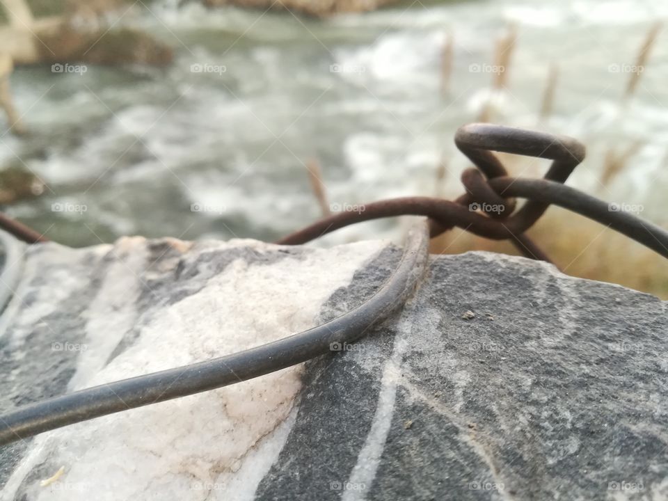 The steel wire that was tied on the big rock beside the river bank.