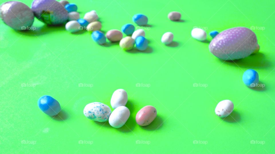 Candy Easter eggs on a bright green background 