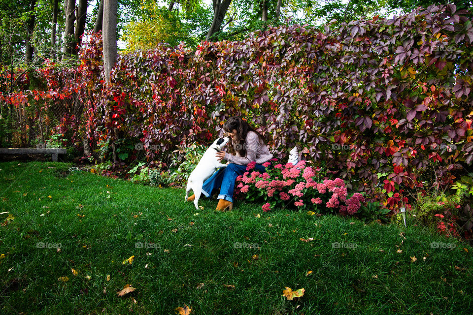 Woman with her dog playing and smiling looking at each other - Happiness in an Autumn garden fall dog pet love portrait 